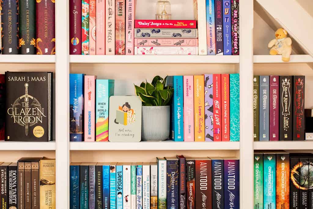 Deel uit de boekenkast, gevuld met boeken, een plant en kaartje